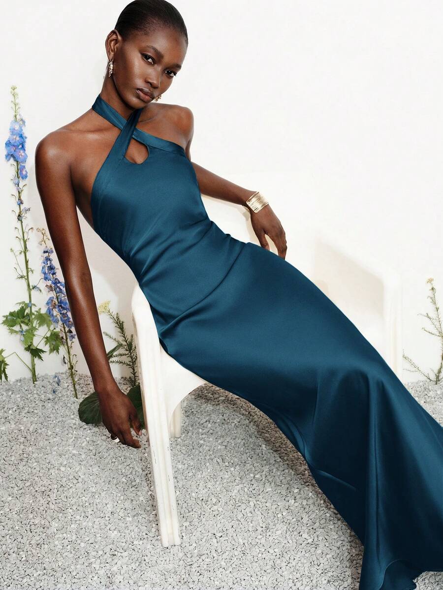 Women's black satin halter neck bodycon midi dress featuring a sleeveless backless design with front slit hem and wrap details.