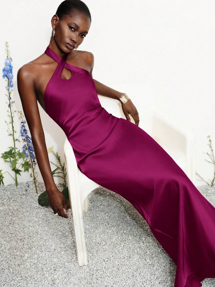 Women's black satin halter neck bodycon midi dress featuring a sleeveless backless design with front slit hem and wrap details.