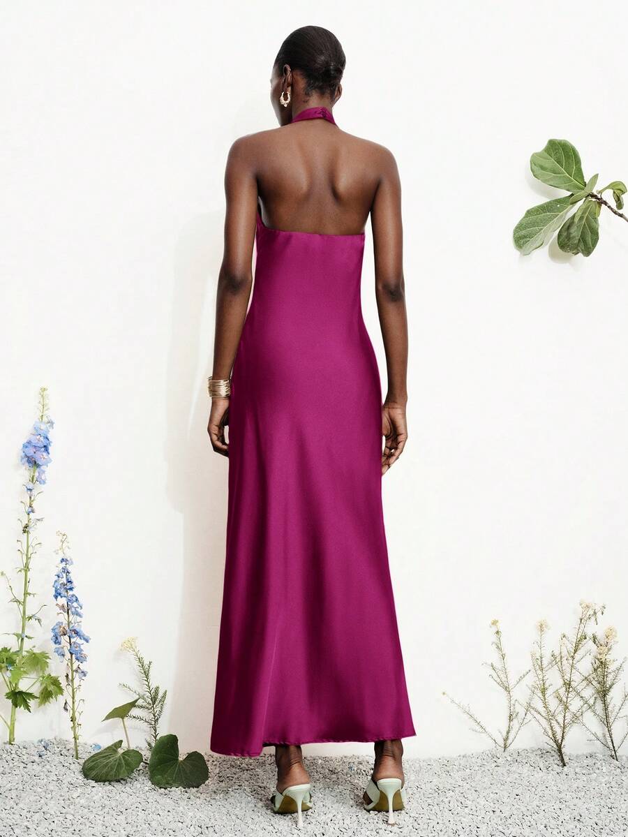 Women's black satin halter neck bodycon midi dress featuring a sleeveless backless design with front slit hem and wrap details.