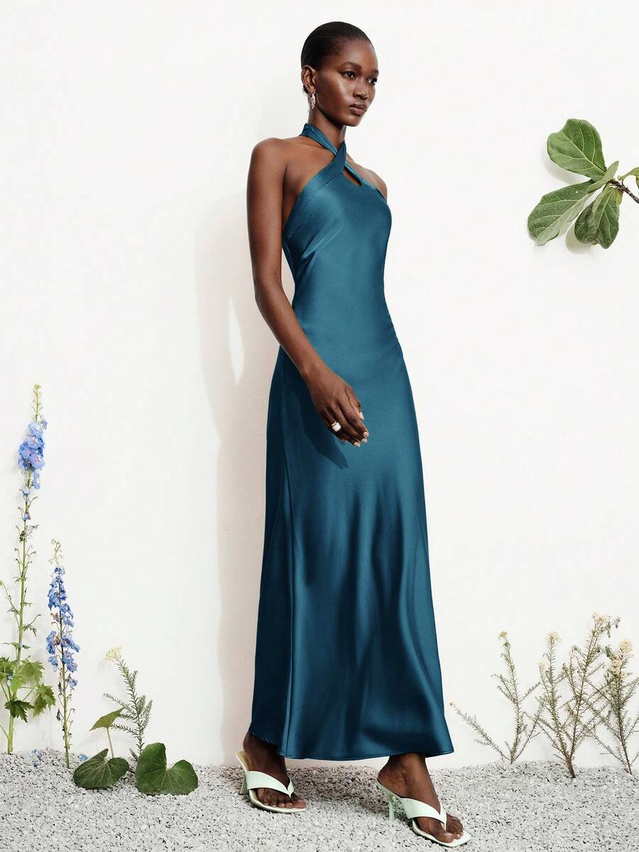 Women's black satin halter neck bodycon midi dress featuring a sleeveless backless design with front slit hem and wrap details.