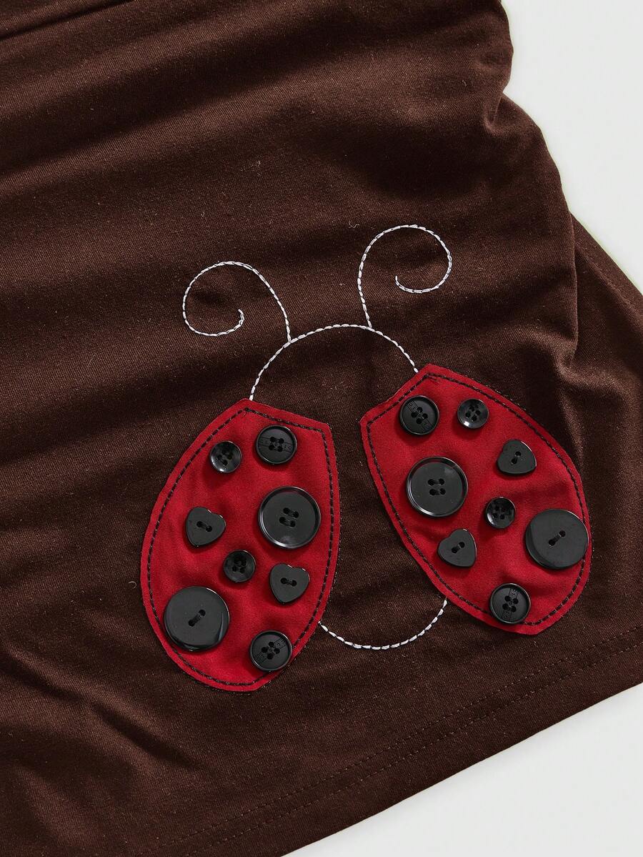 Women's black cropped strapless camisole top with ladybug embroidery and rhinestone details.