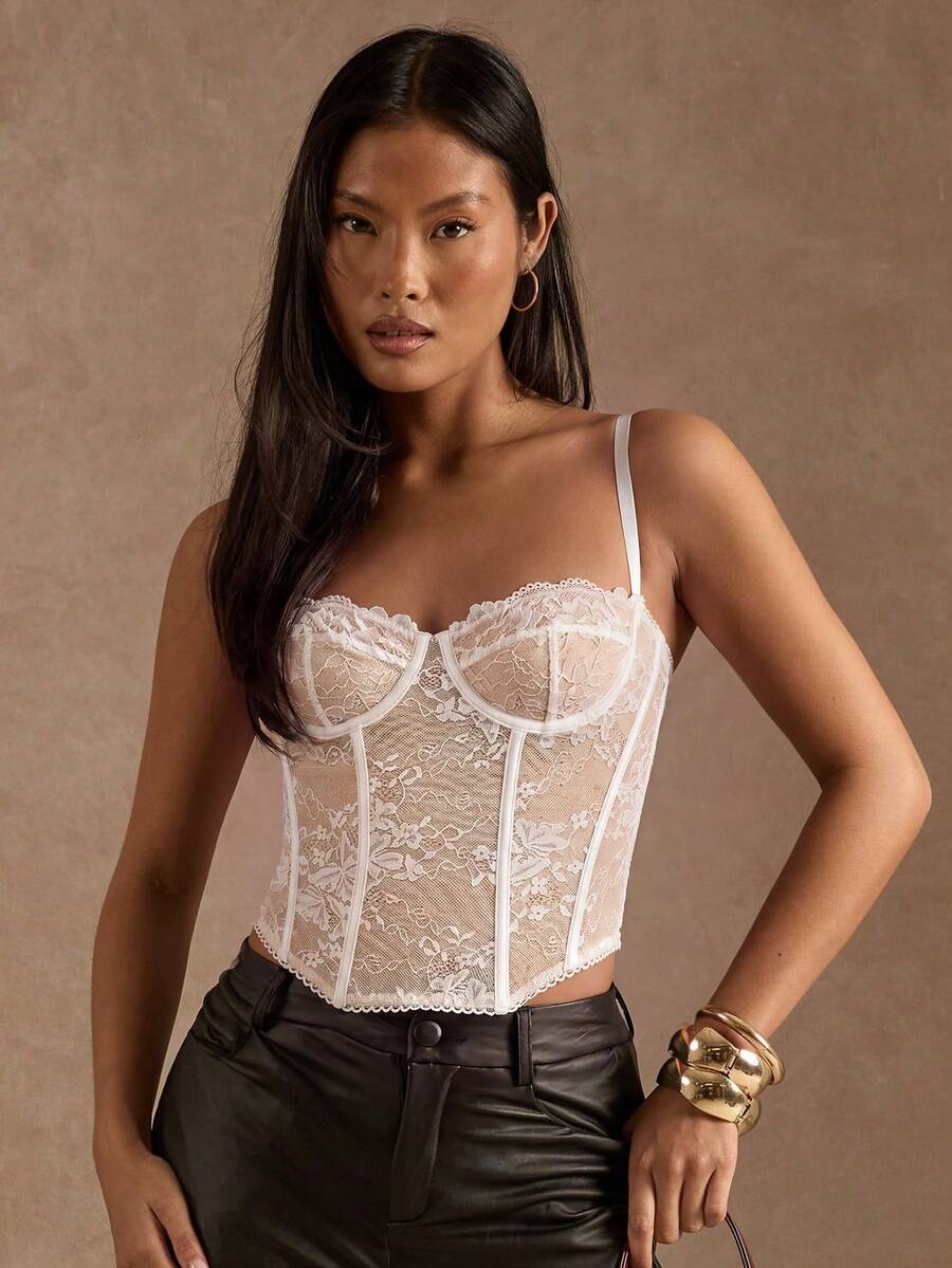 Black women’s lace cami top with spaghetti straps, contrast lace details, and an asymmetrical hem, styled as a slim-fit lined casual top.