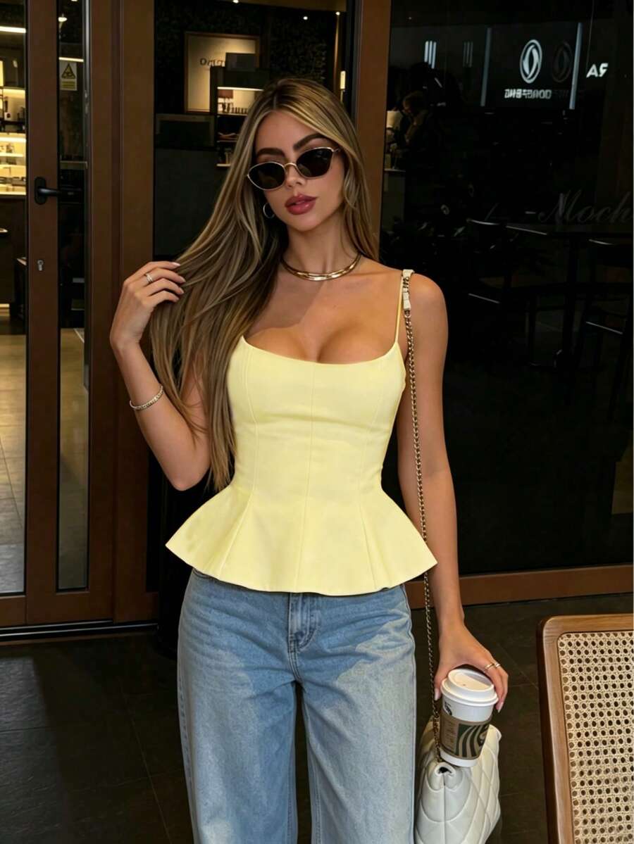 A sleeveless cropped camisole top featuring thin spaghetti straps, a slim fit bodice, and a subtle flared hemline.