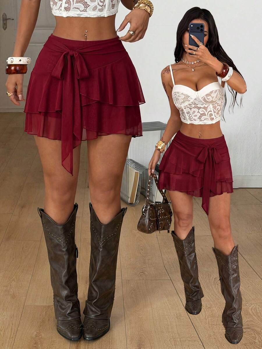 Black low waist tiered mini skirt featuring a ruffle hem and ring accent detail on knitted stretch fabric for women.