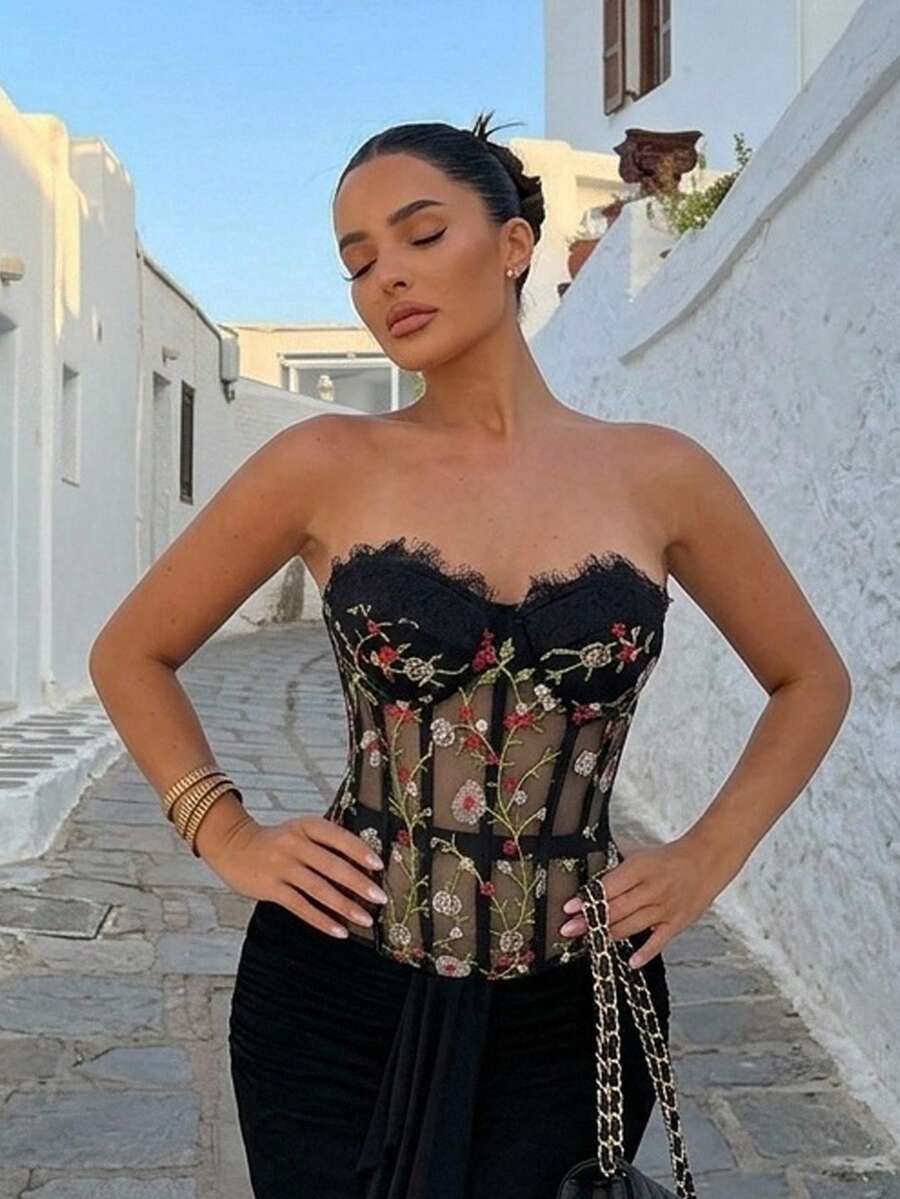 Women's black lace boned strapless bandeau crop top featuring semi-sheer baroque embroidered detail, slim fit silhouette, and asymmetrical hem.
