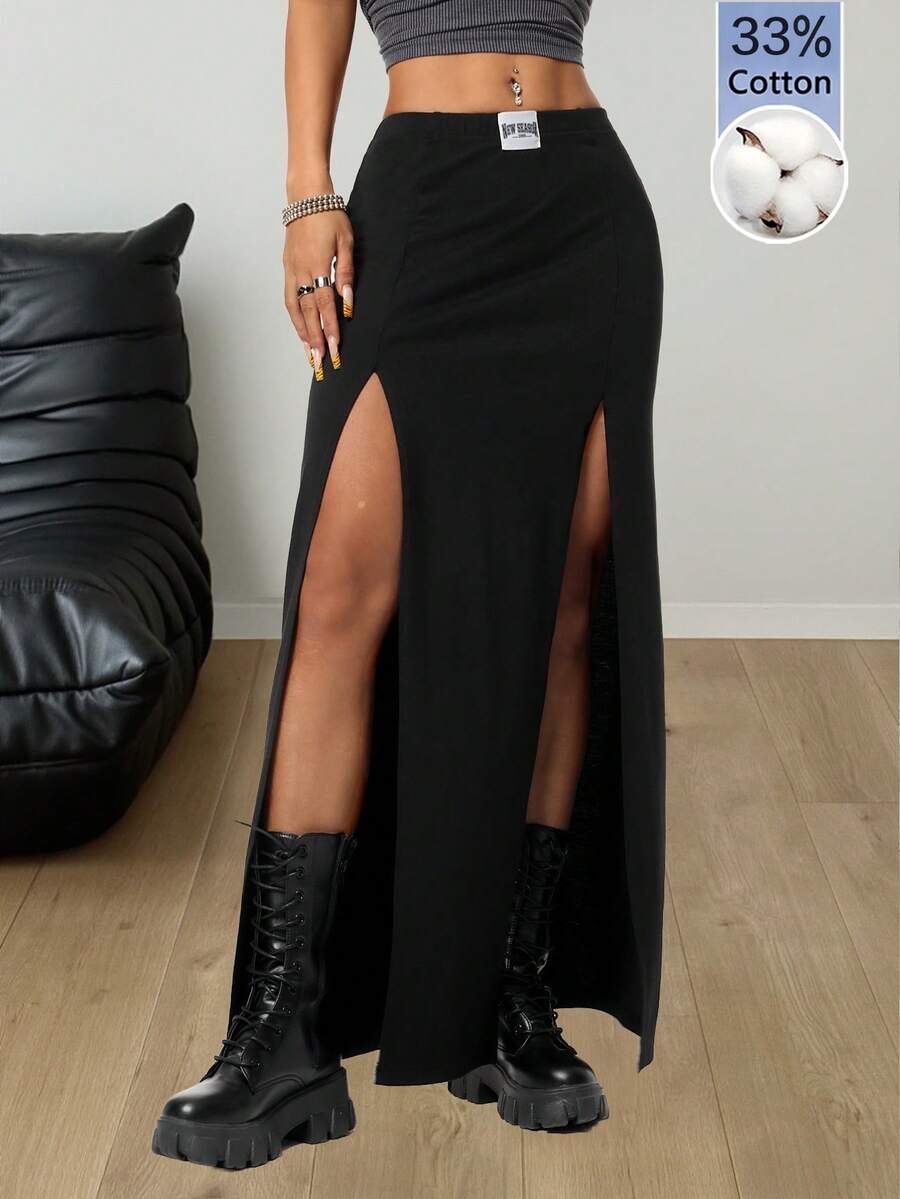 Women's black high waist long skirt with split thigh slit, zipper, and letter patch detail made from knitted stretch fabric.