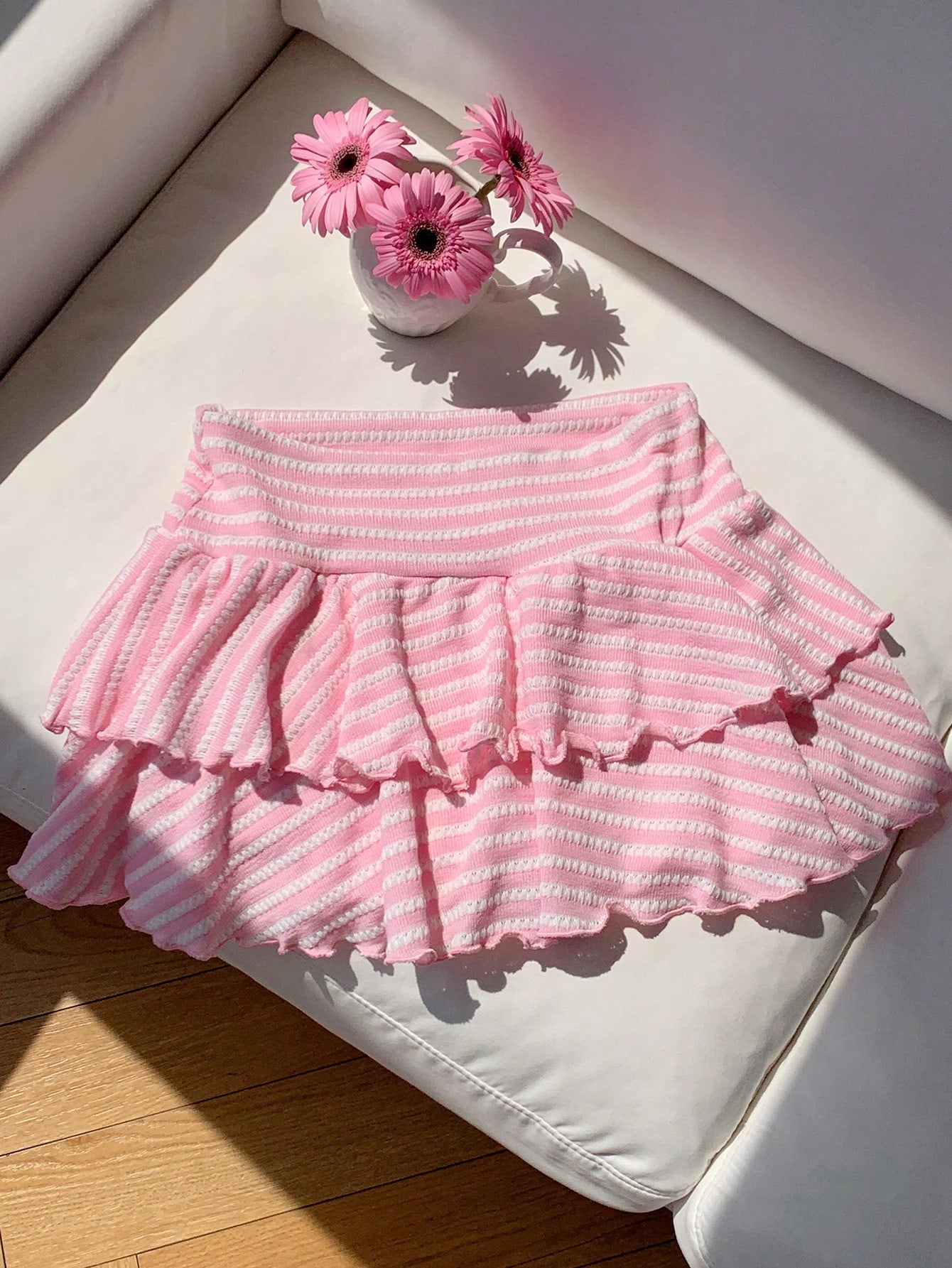 Black low waist knit mini skirt featuring a tiered ruffle hem and skinny high stretch fit.