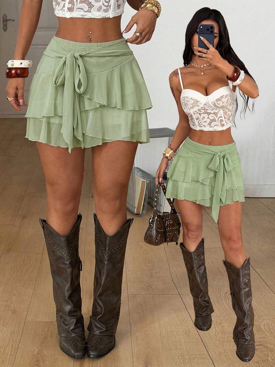 Black low waist tiered mini skirt featuring a ruffle hem and ring accent detail on knitted stretch fabric for women.