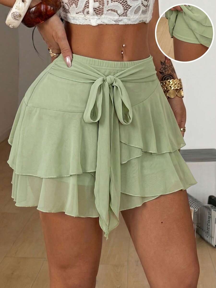 Black low waist tiered mini skirt featuring a ruffle hem and ring accent detail on knitted stretch fabric for women.