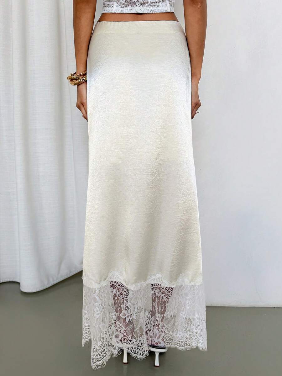 Woman wearing an elegant apricot satin maxi skirt featuring delicate contrast lace trim, a low waist design, and a flowing A-line silhouette.