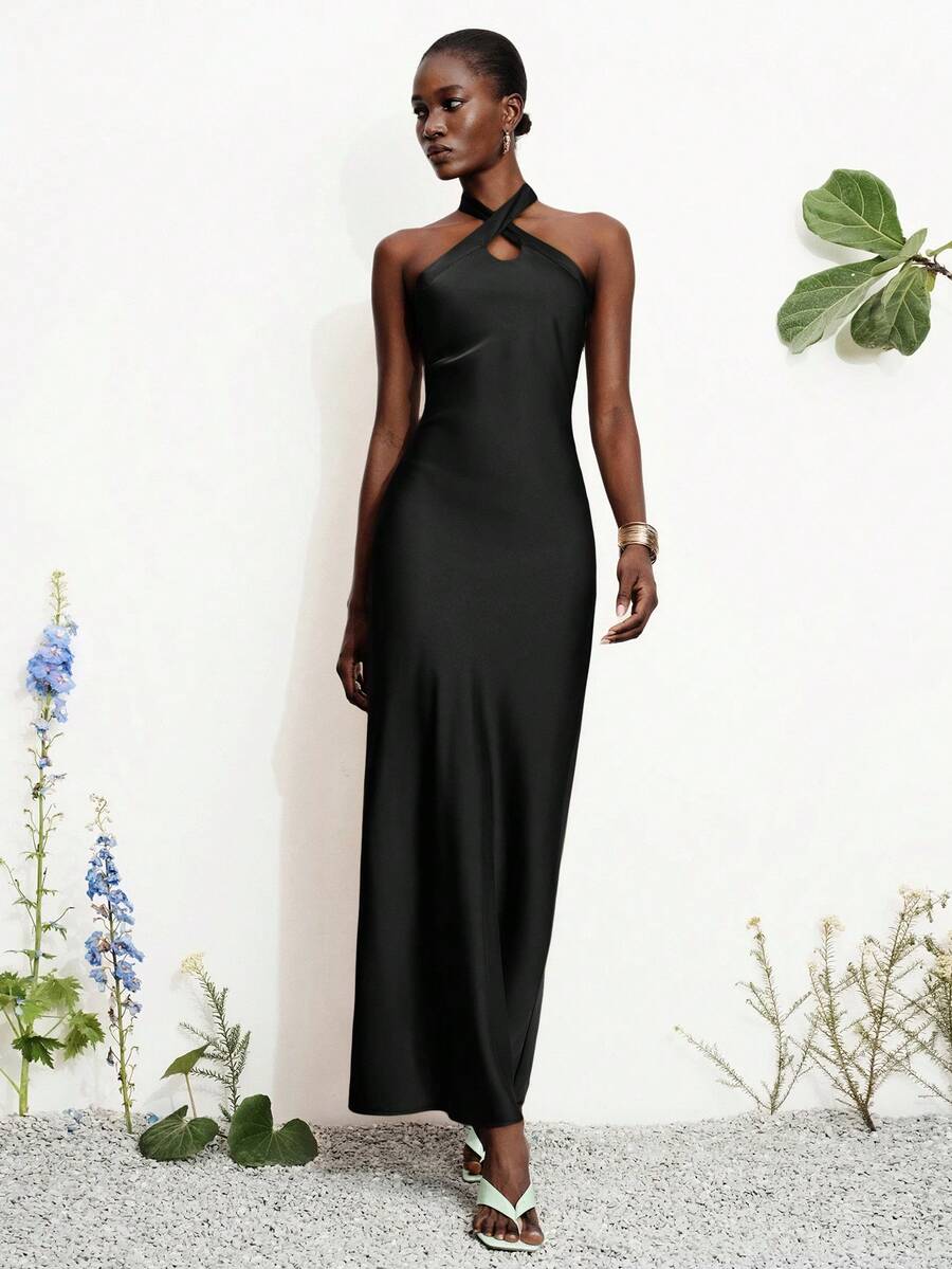 Women's black satin halter neck bodycon midi dress featuring a sleeveless backless design with front slit hem and wrap details.