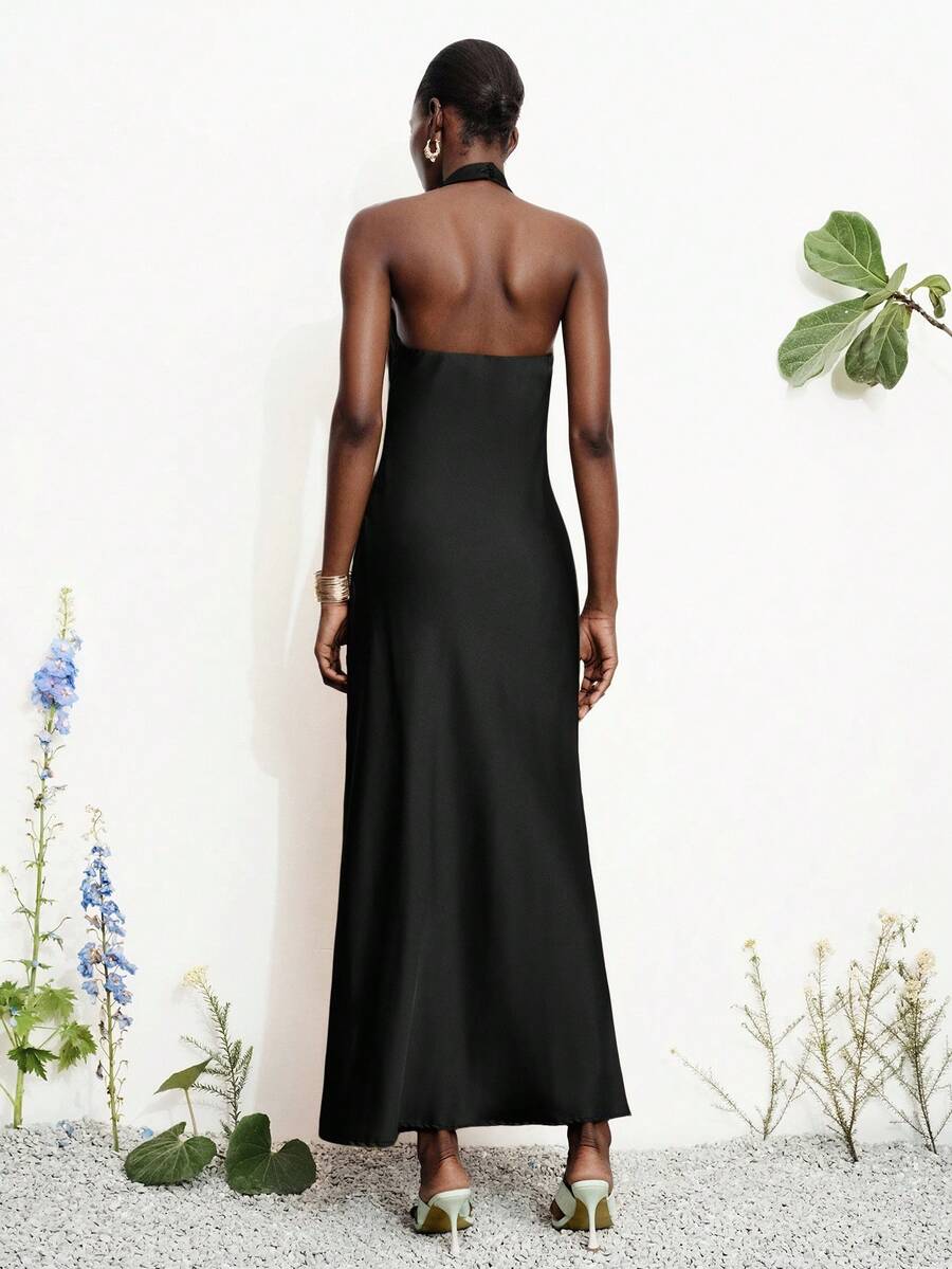 Women's black satin halter neck bodycon midi dress featuring a sleeveless backless design with front slit hem and wrap details.