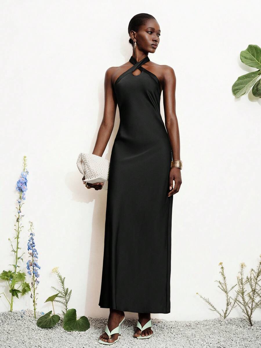 Women's black satin halter neck bodycon midi dress featuring a sleeveless backless design with front slit hem and wrap details.