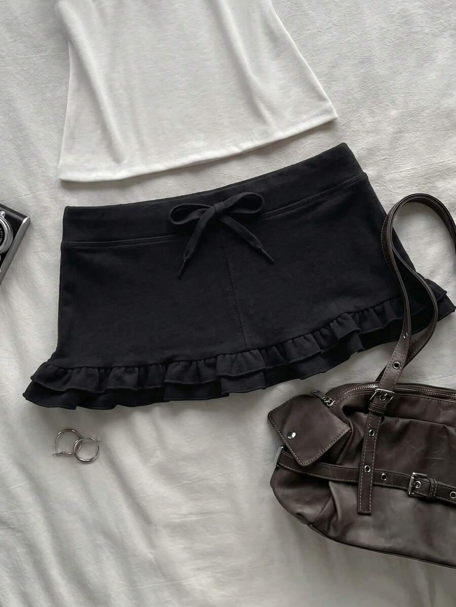 Women's plain black ultra low waist bodycon mini skirt with frill detailing in knitted stretch fabric.