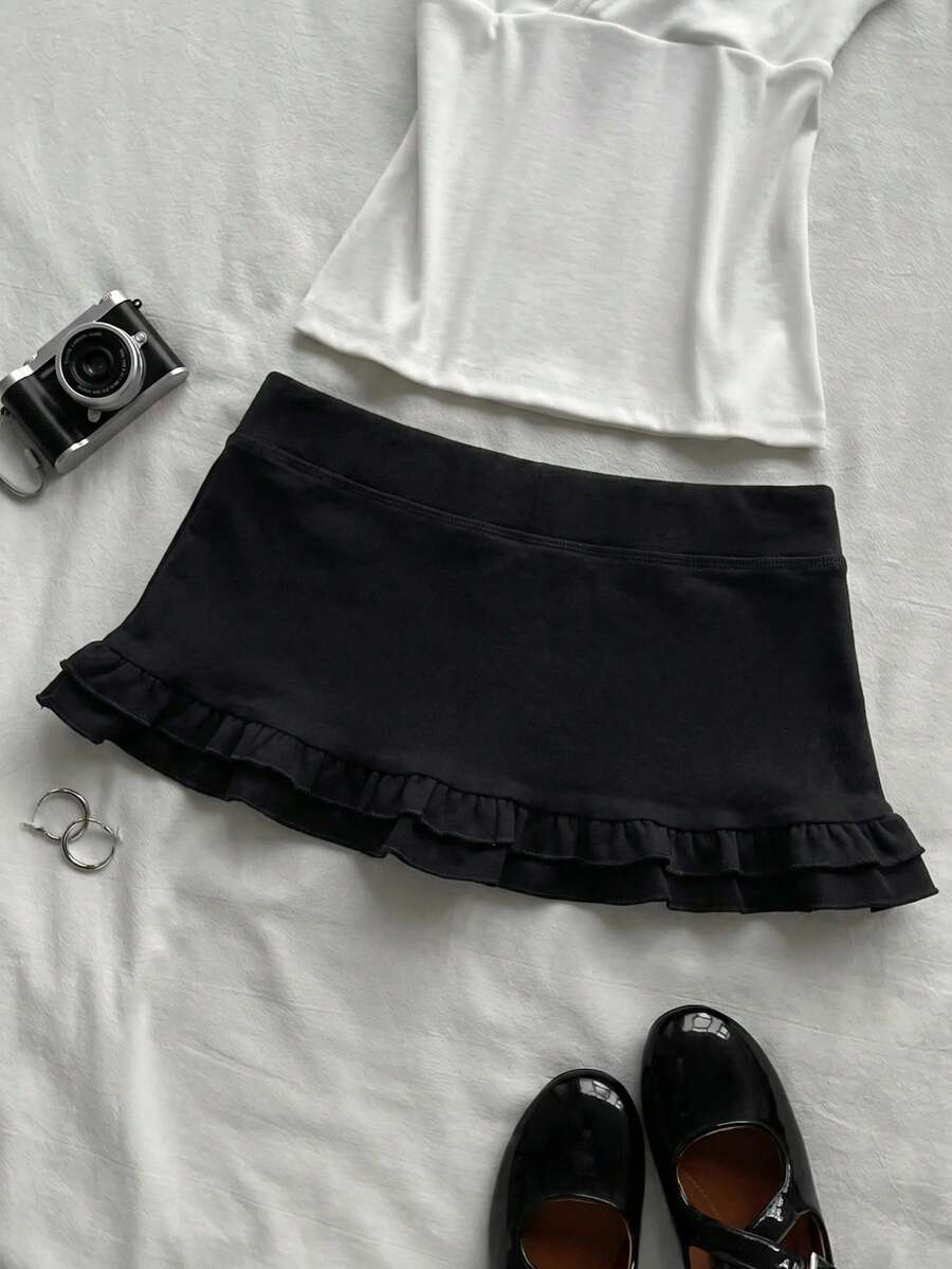 Women's plain black ultra low waist bodycon mini skirt with frill detailing in knitted stretch fabric.