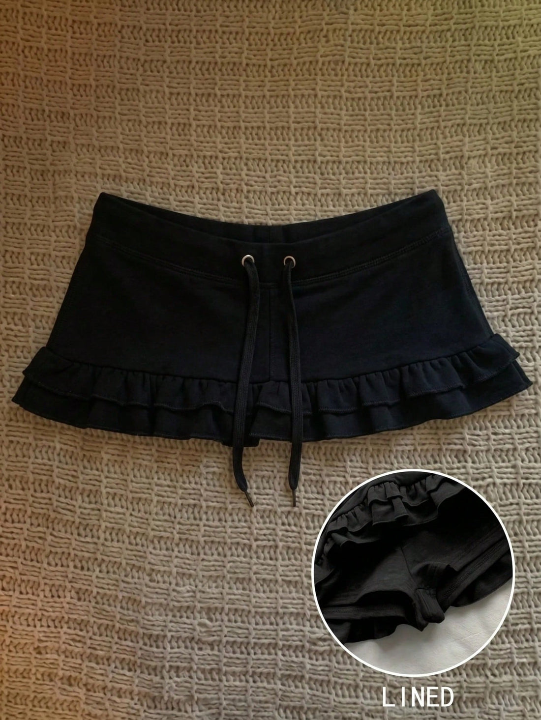Women's plain black ultra low waist bodycon mini skirt with frill detailing in knitted stretch fabric.