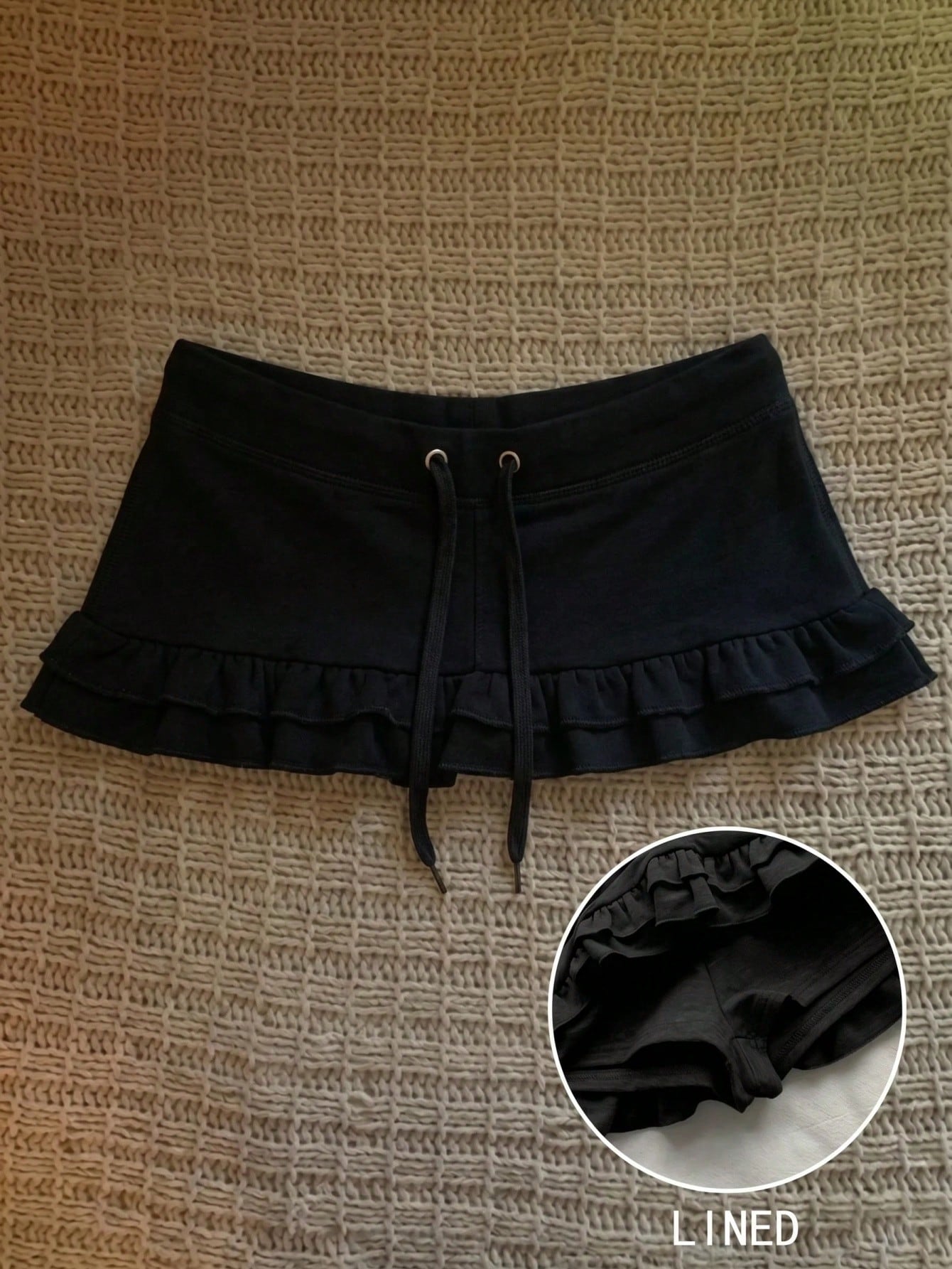 Women's plain black ultra low waist bodycon mini skirt with frill detailing in knitted stretch fabric.