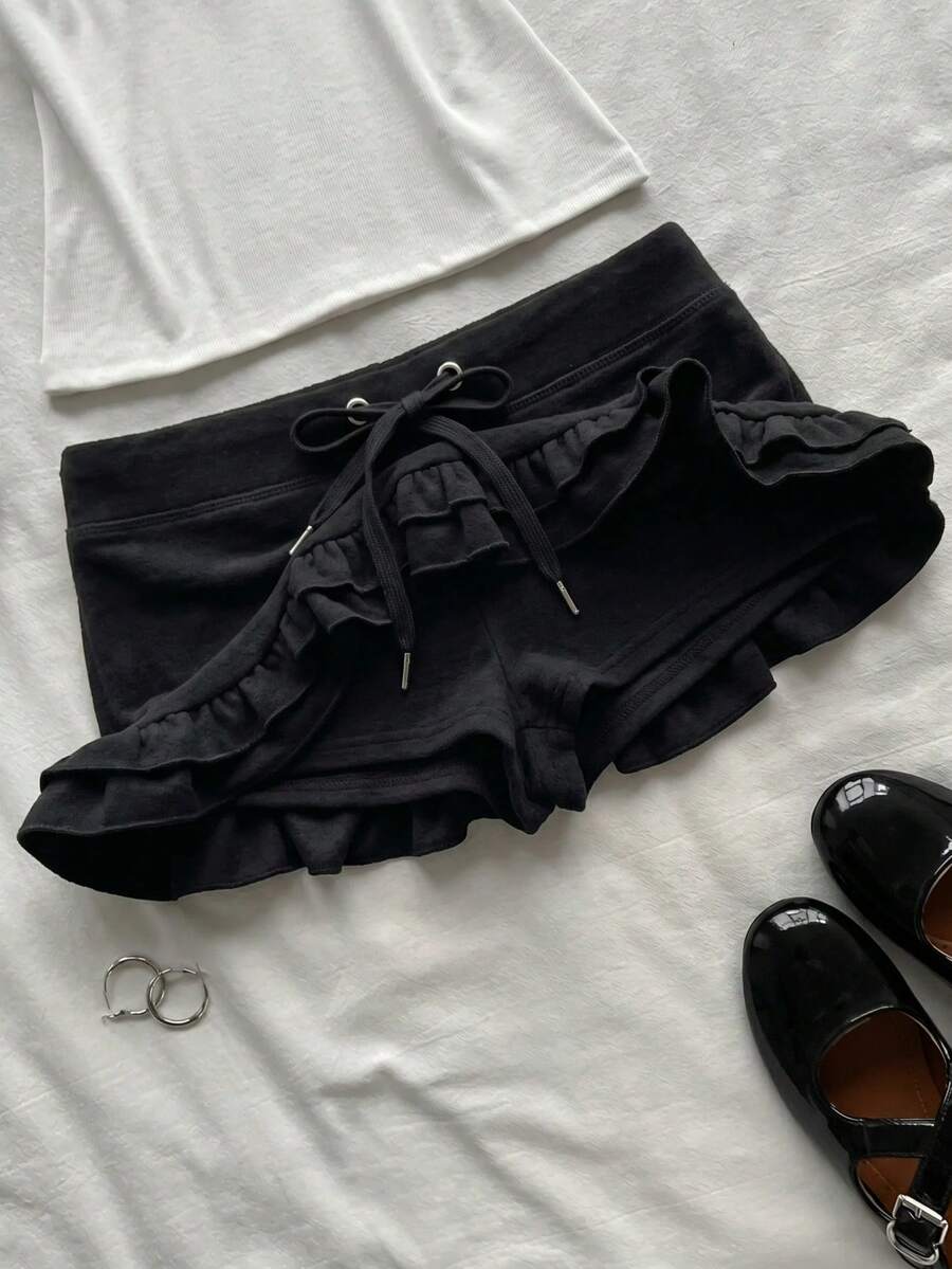 Women's plain black ultra low waist bodycon mini skirt with frill detailing in knitted stretch fabric.