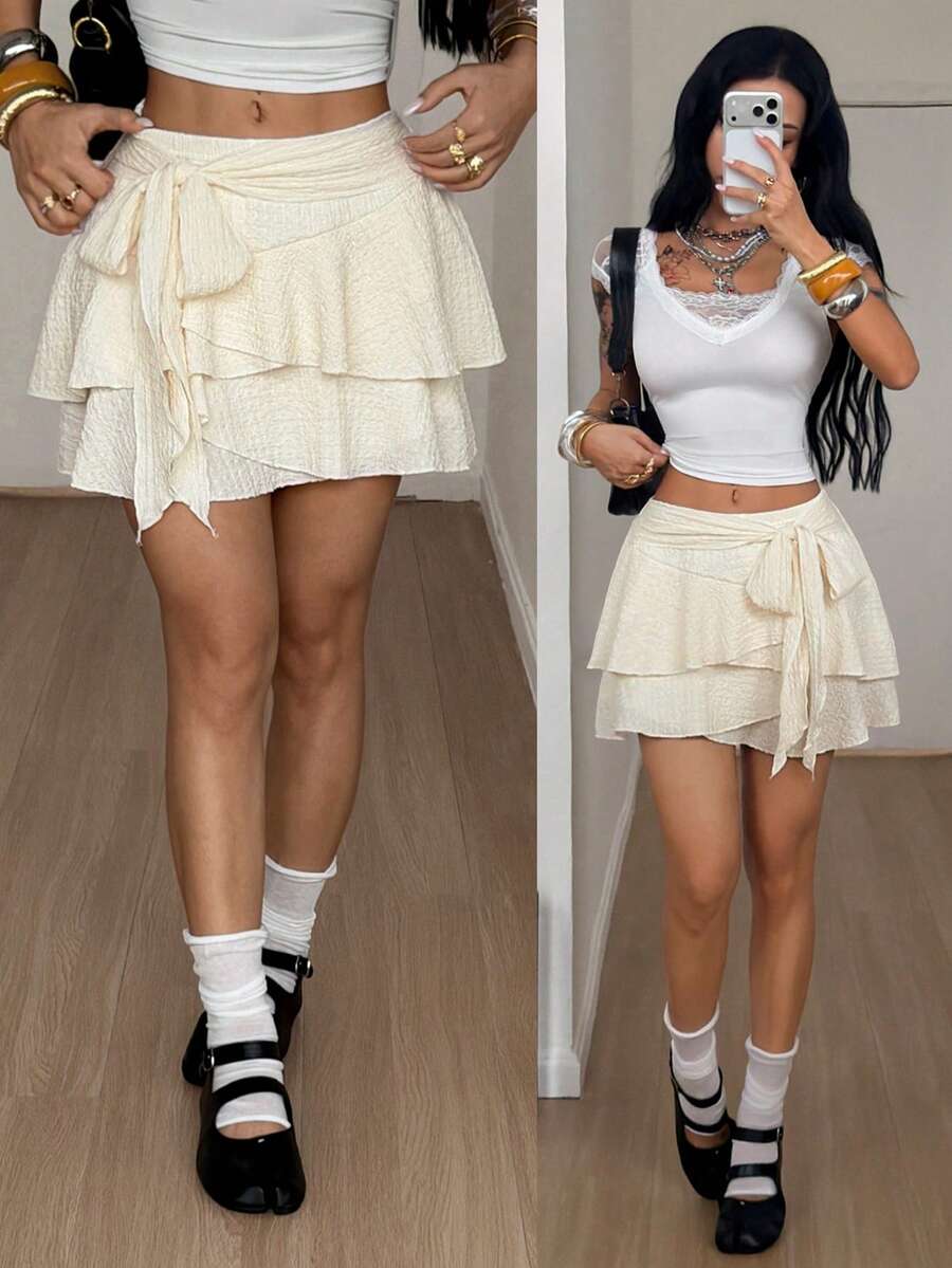 Black low waist tiered mini skirt featuring a ruffle hem and ring accent detail on knitted stretch fabric for women.