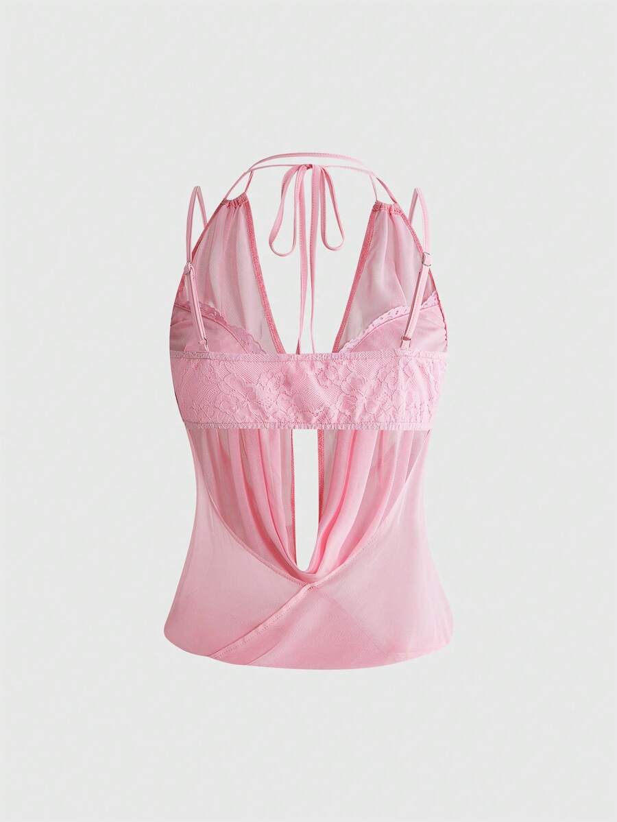 Women wearing a black draped backless halter crop top layered over a boned lace camisole.