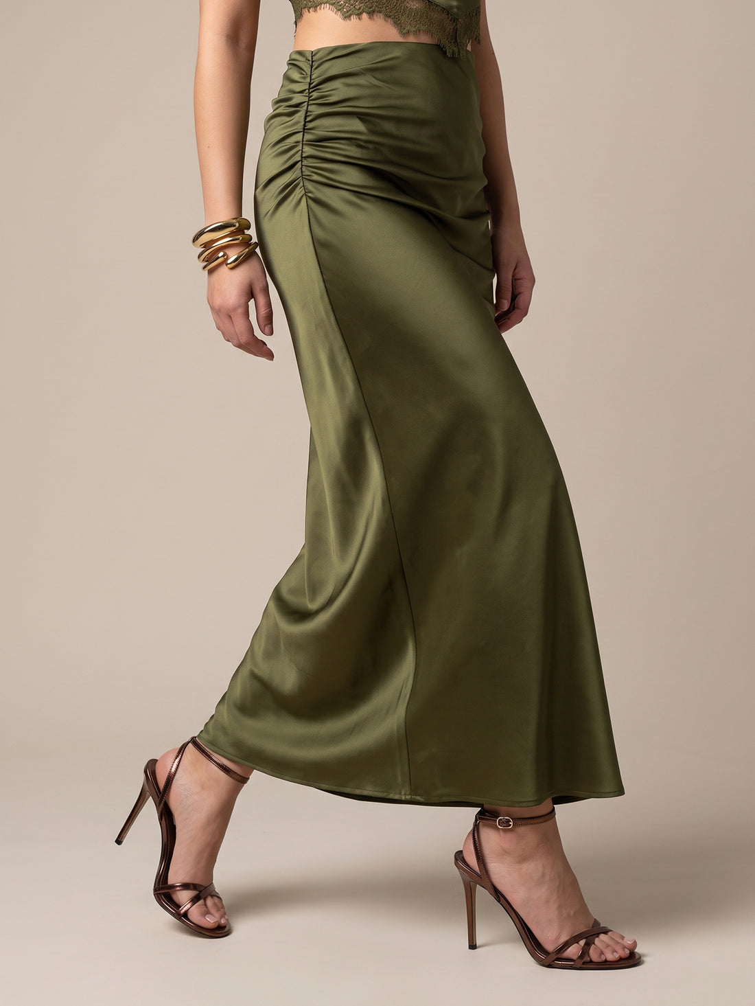 Front view of a woman wearing an army green ruched mermaid maxi skirt featuring a sleek side slit, mid waist line, and zipper back closure for formal evening occasions.