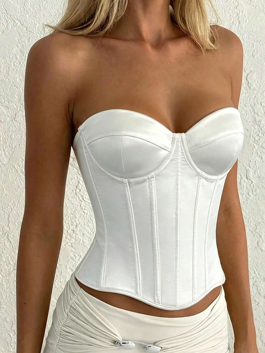 White women’s corset top with metal eyelet details, boning structure, spaghetti straps, backless tie-back design, and a slim cropped fit.