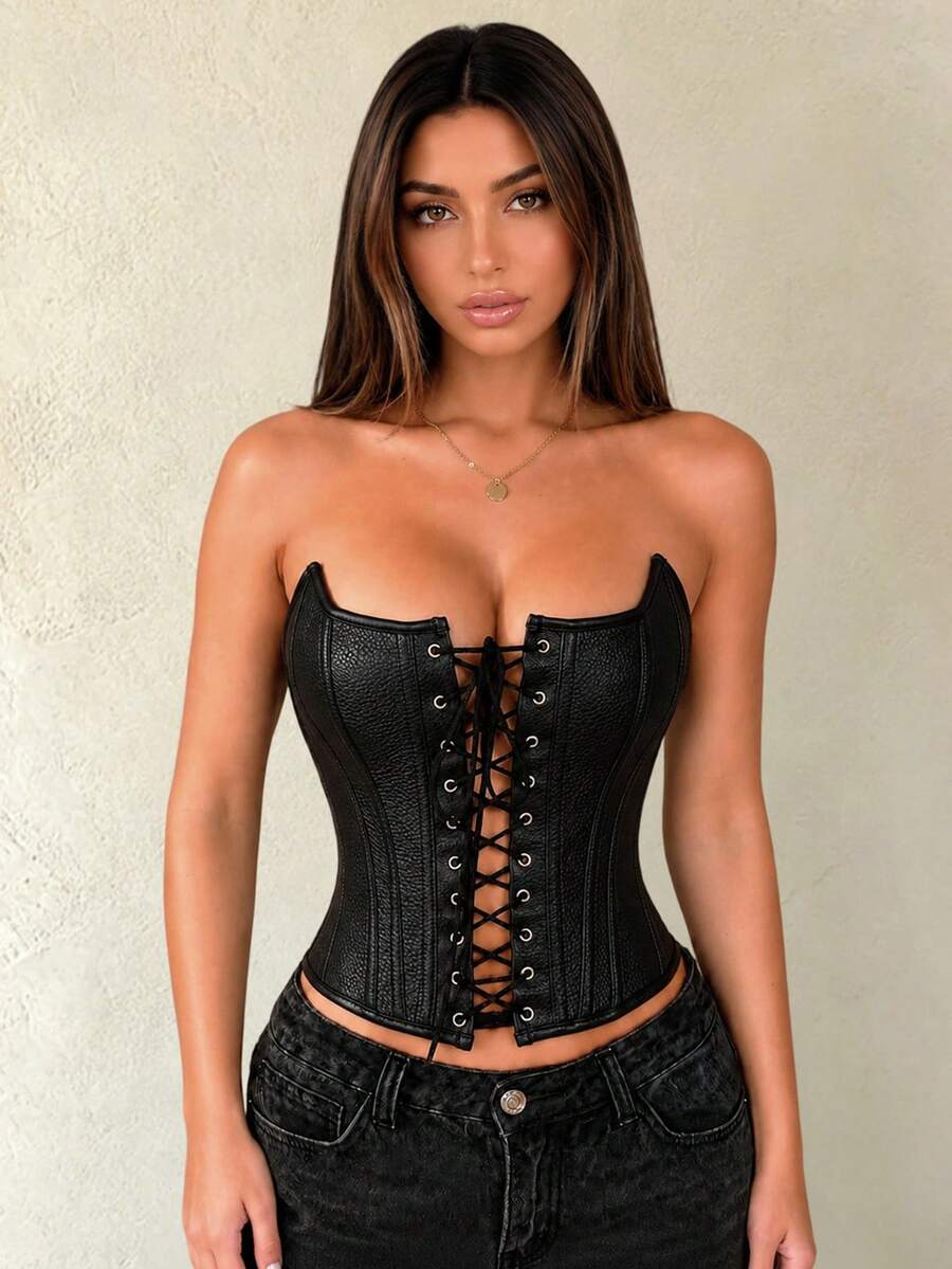 Black PU leather strapless bustier corset crop top featuring boned structure, lace-up grommet eyelets, and an asymmetrical hem on a women model.