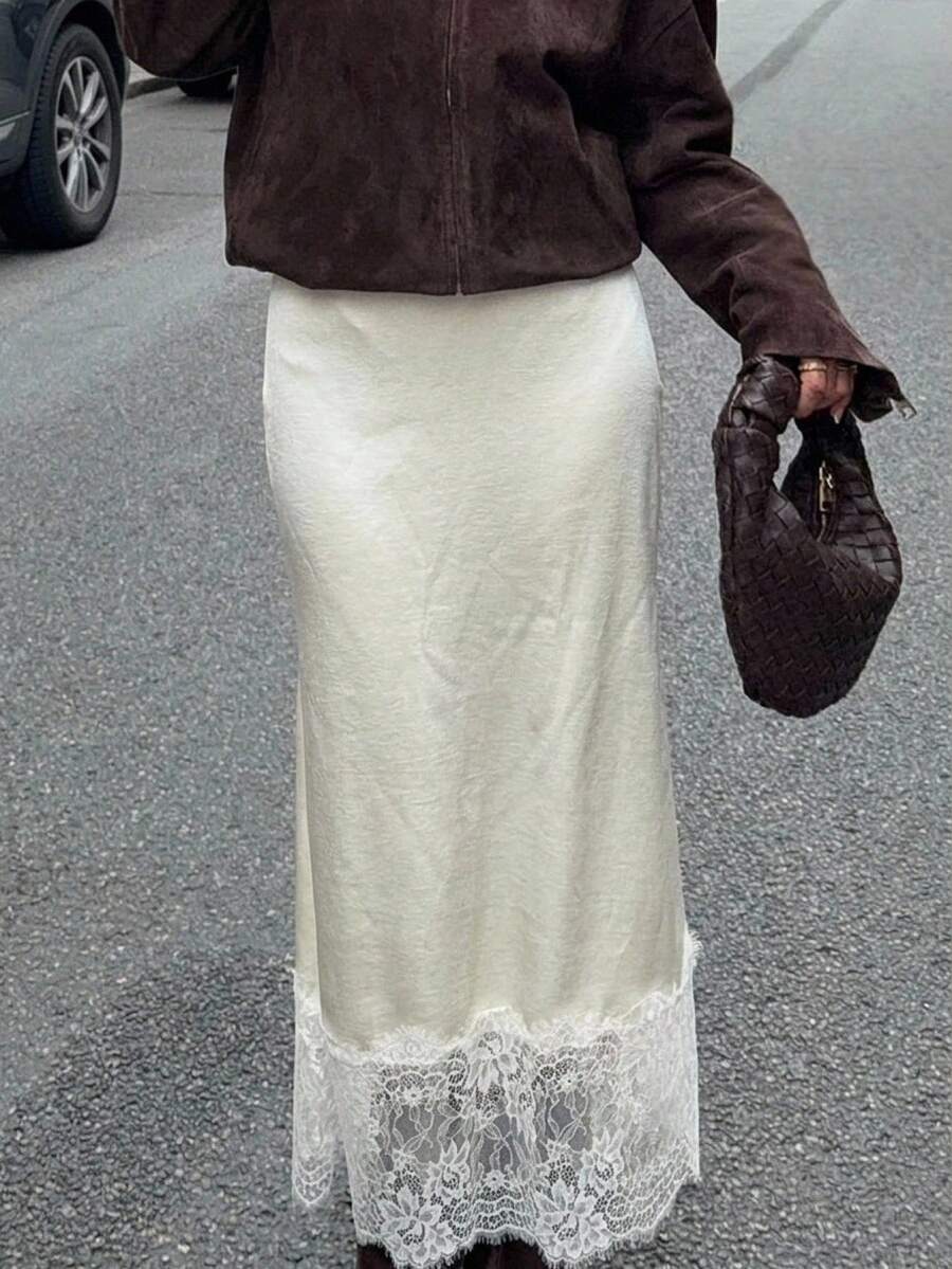 Woman wearing an elegant apricot satin maxi skirt featuring delicate contrast lace trim, a low waist design, and a flowing A-line silhouette.