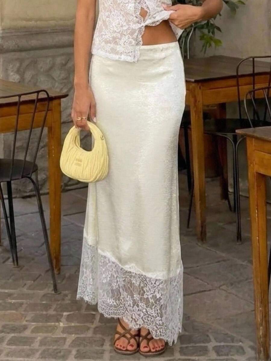 Woman wearing an elegant apricot satin maxi skirt featuring delicate contrast lace trim, a low waist design, and a flowing A-line silhouette.