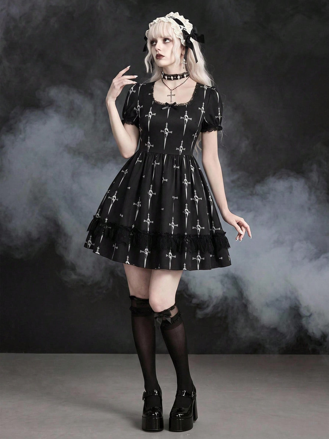 Black Gothic mini dress featuring cross skull print, square neckline with contrast lace trim, short puff sleeves, front drawstring detail, and high-waist flared A-line silhouette.