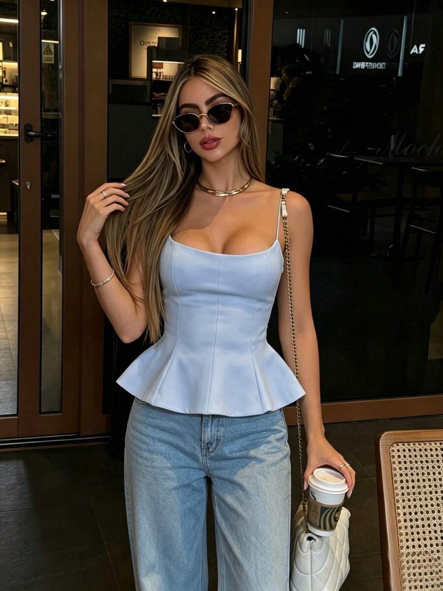 A sleeveless cropped camisole top featuring thin spaghetti straps, a slim fit bodice, and a subtle flared hemline.