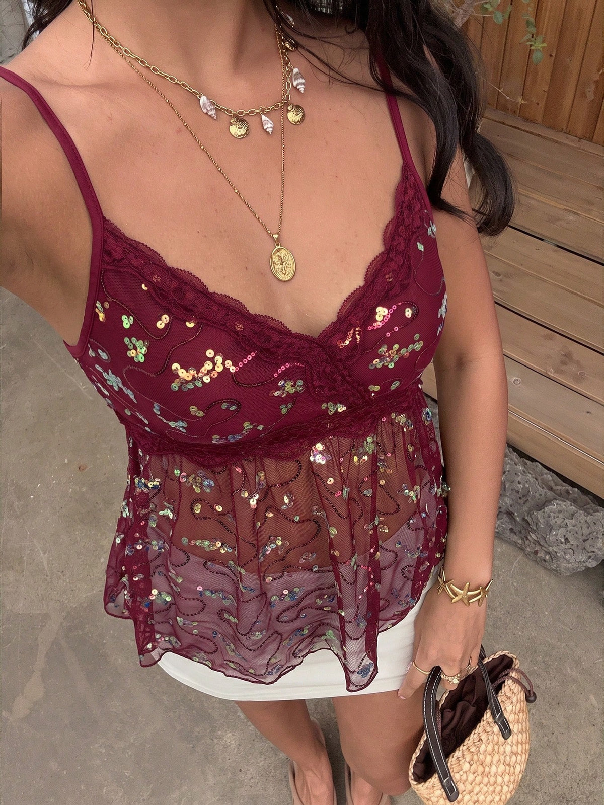 Women's black sequin lace patchwork camisole top featuring thin spaghetti straps, contrast lace trim, and an asymmetrical ruffle hem with knot details.