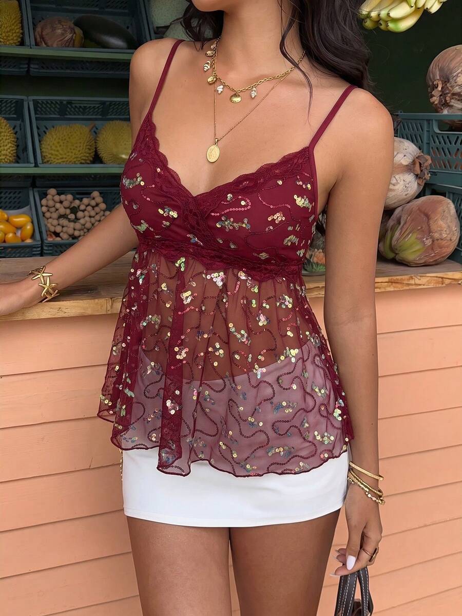 Women's black sequin lace patchwork camisole top featuring thin spaghetti straps, contrast lace trim, and an asymmetrical ruffle hem with knot details.