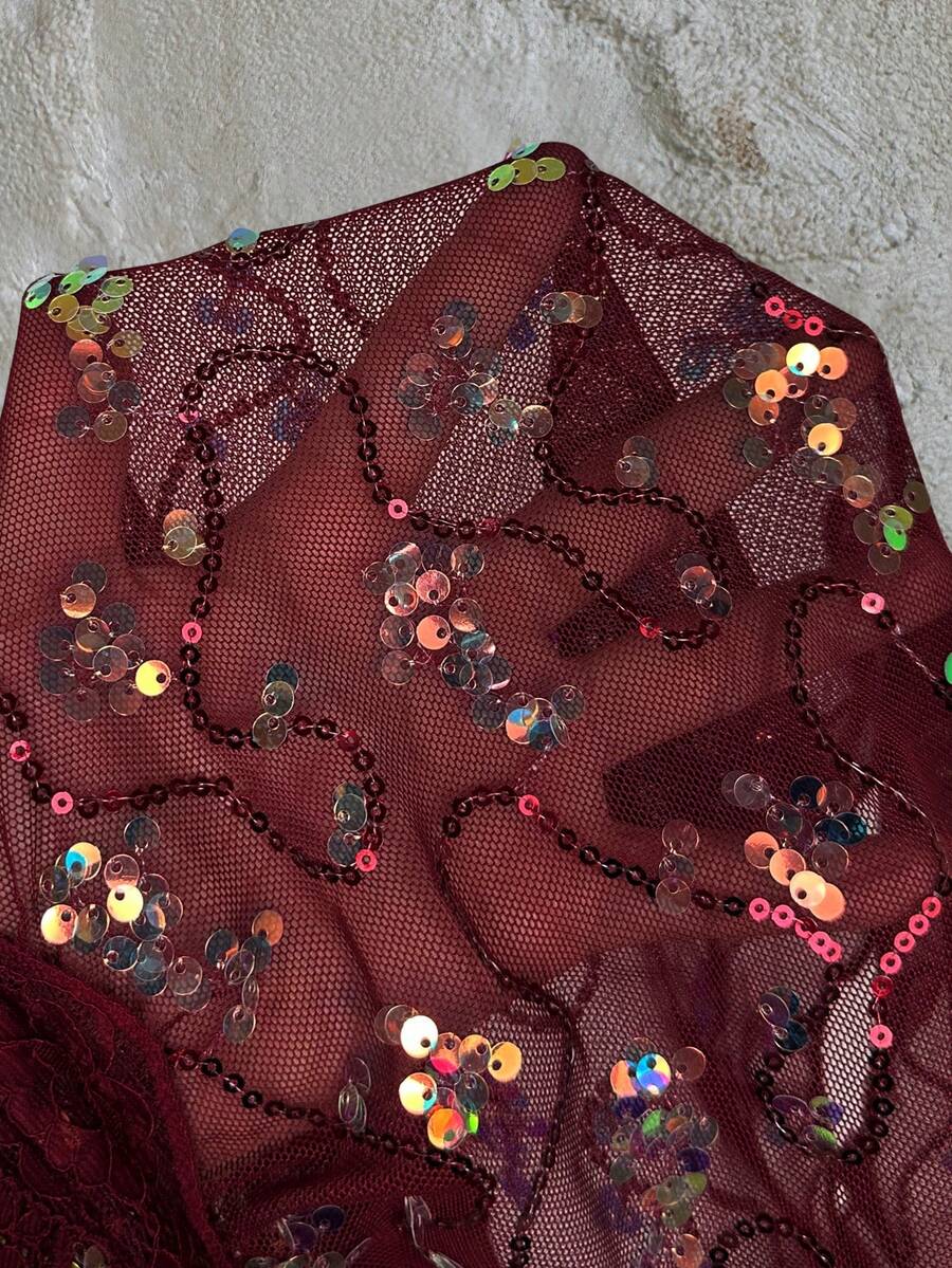 Women's black sequin lace patchwork camisole top featuring thin spaghetti straps, contrast lace trim, and an asymmetrical ruffle hem with knot details.