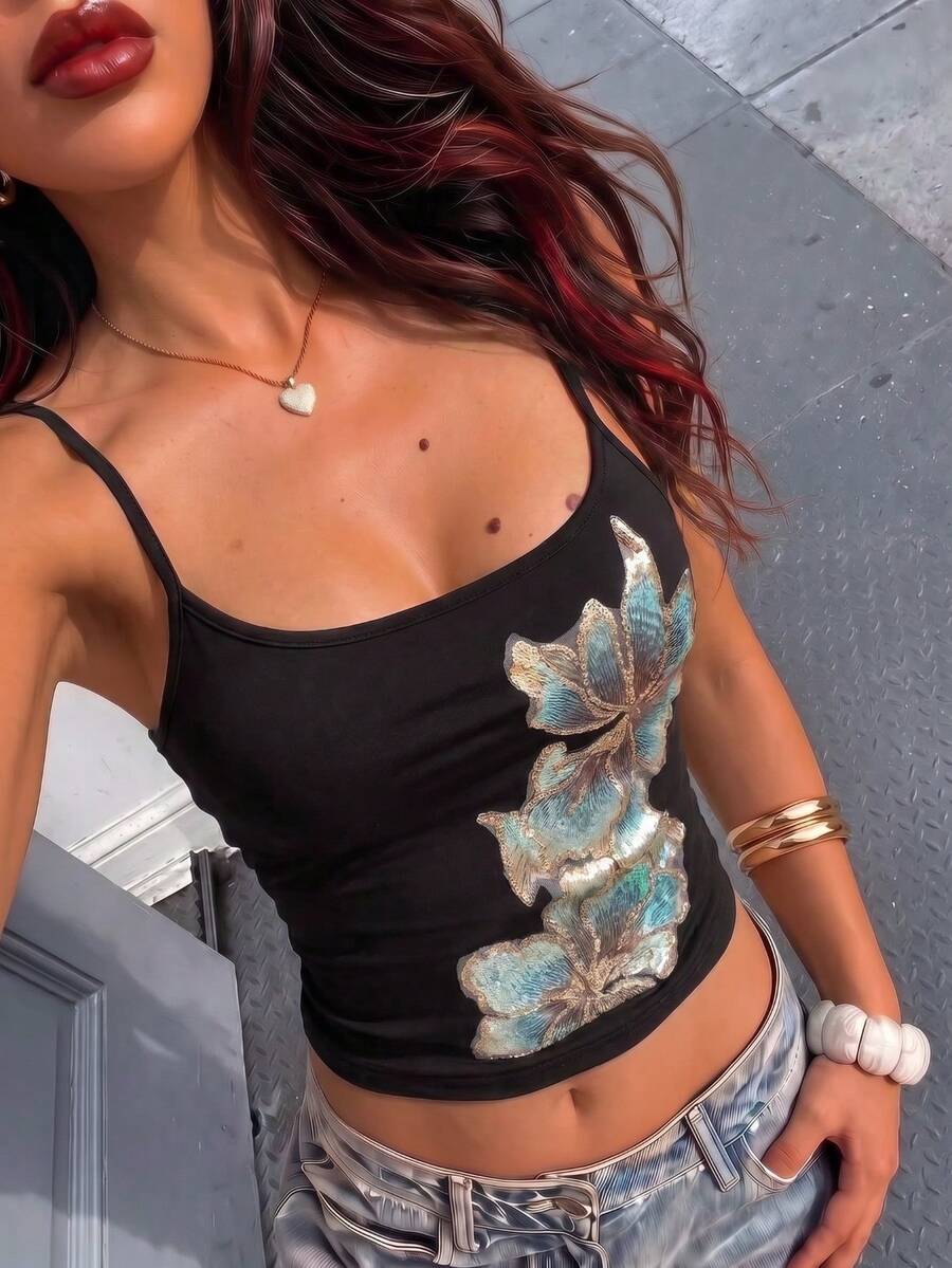 Women's black floral backless camisole top featuring spaghetti straps and front ring detail on knitted stretch fabric.