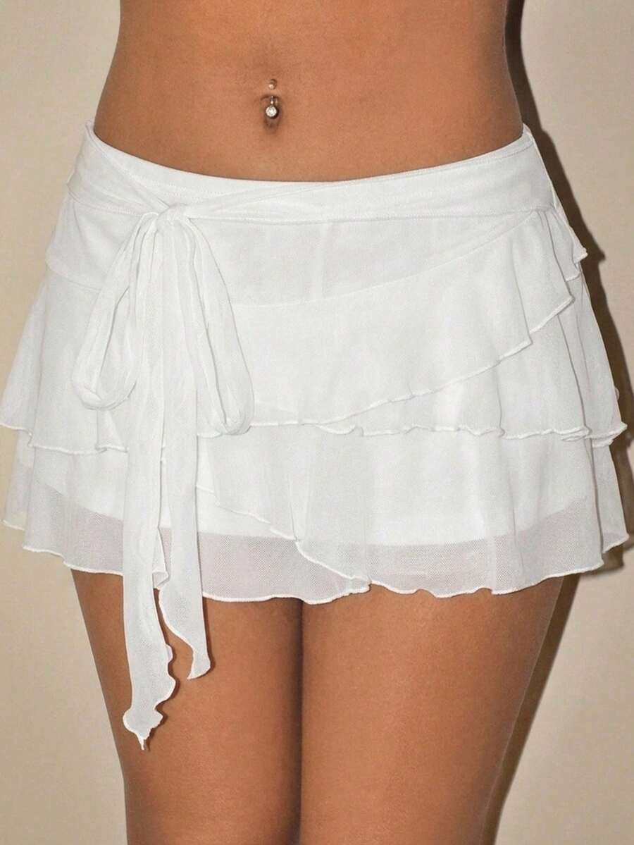 White tiered ruffle trim mini skirt for women with low waist, knot detail, mesh fabric, and casual Y2K boho design.