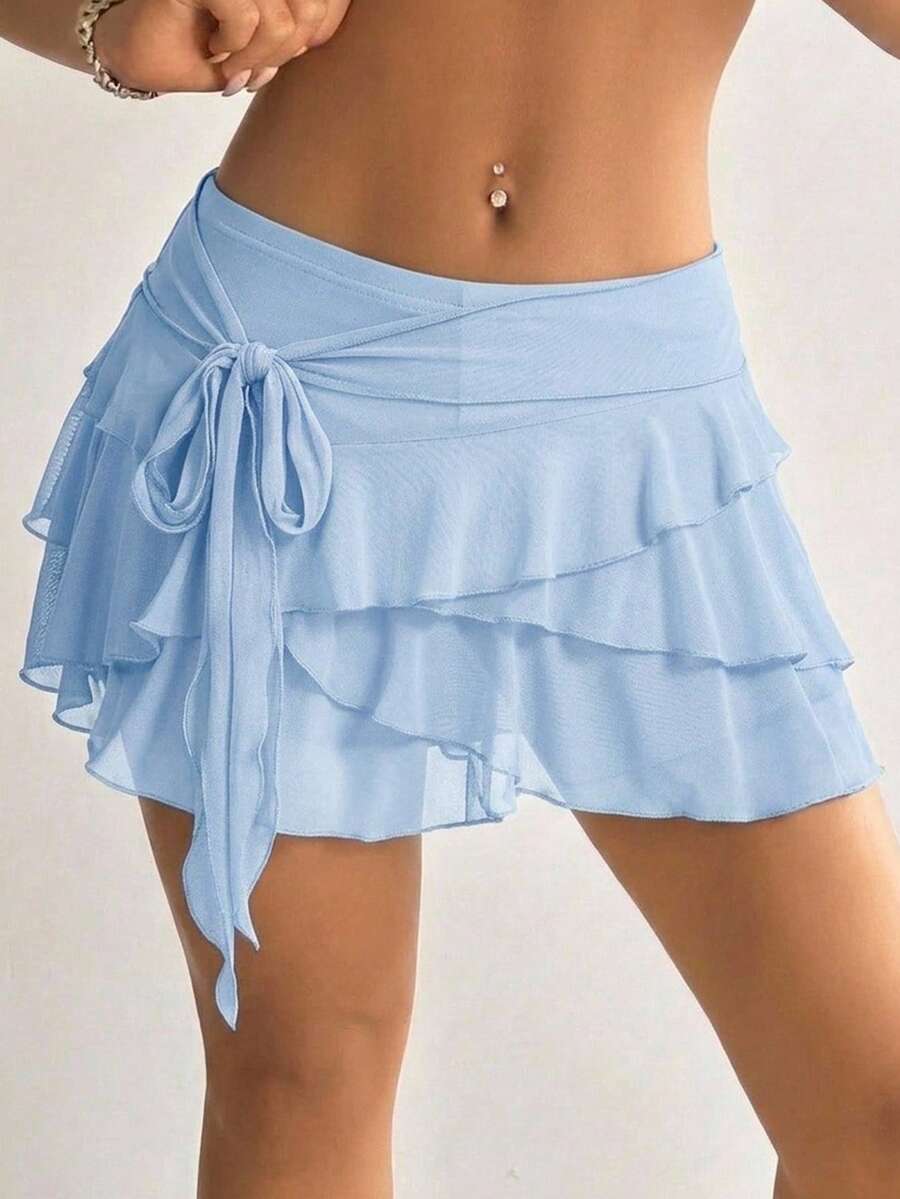 White tiered ruffle trim mini skirt for women with low waist, knot detail, mesh fabric, and casual Y2K boho design.