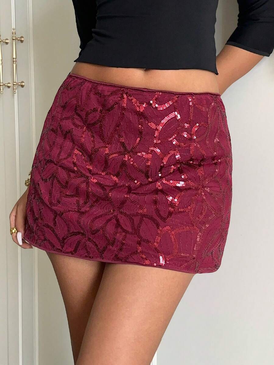 Burgundy shiny sequin bodycon mini skirt for women with low waist design, floral plant embroidery, and zipper detail.