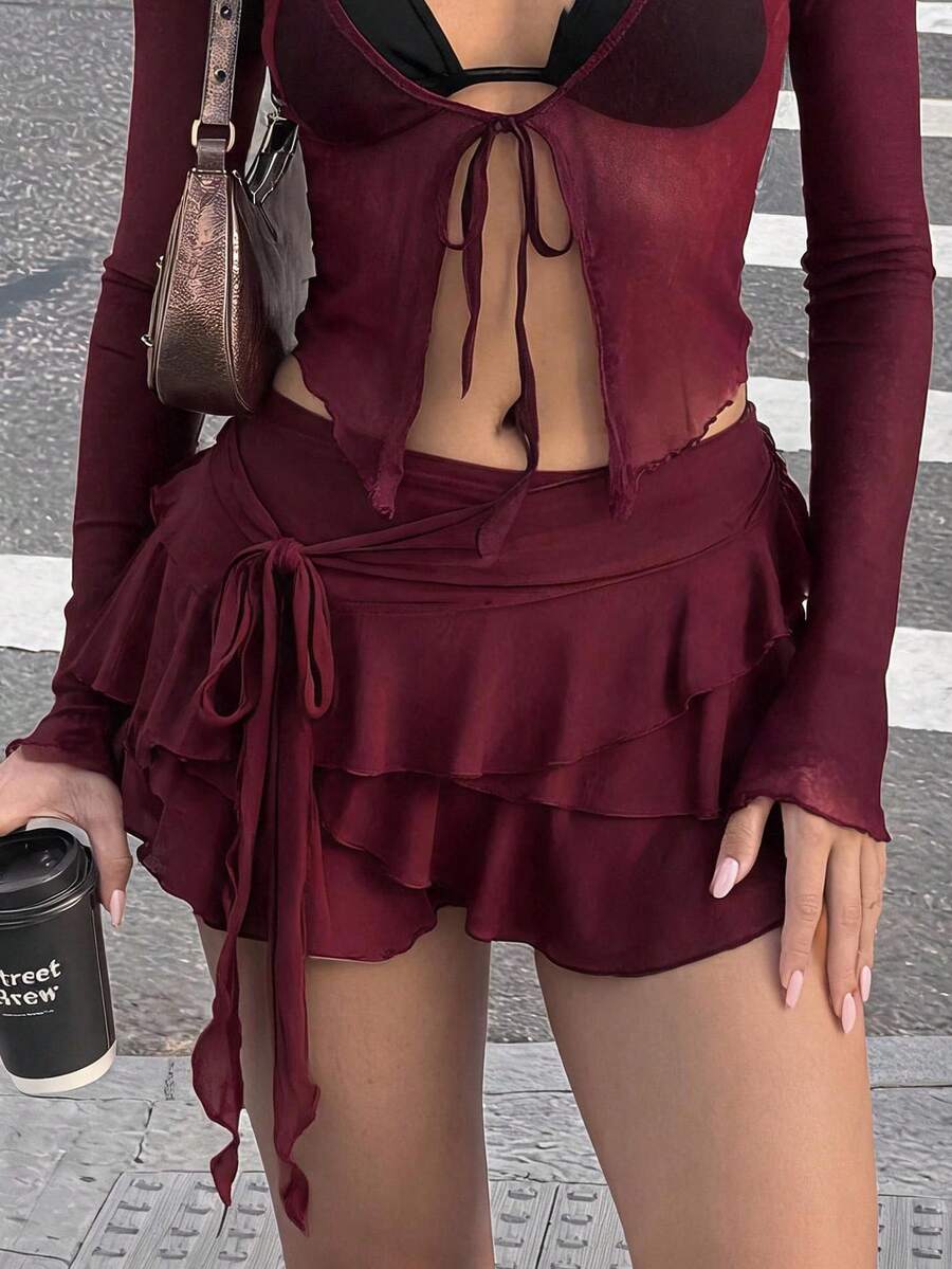 White tiered ruffle trim mini skirt for women with low waist, knot detail, mesh fabric, and casual Y2K boho design.