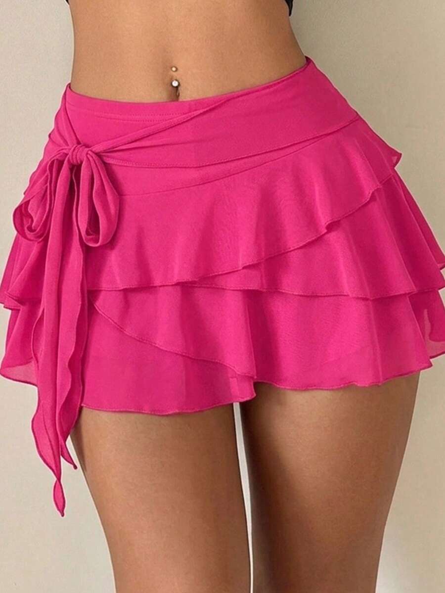 White tiered ruffle trim mini skirt for women with low waist, knot detail, mesh fabric, and casual Y2K boho design.