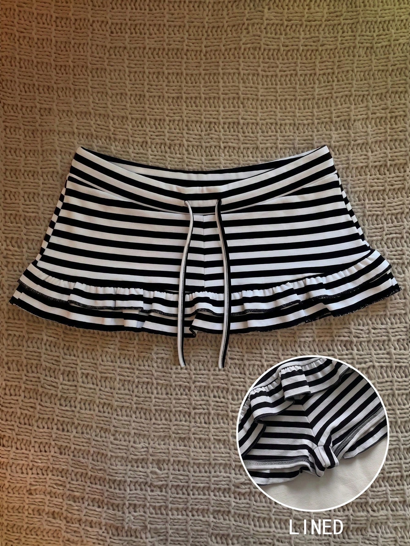Women's plain black ultra low waist bodycon mini skirt with frill detailing in knitted stretch fabric.