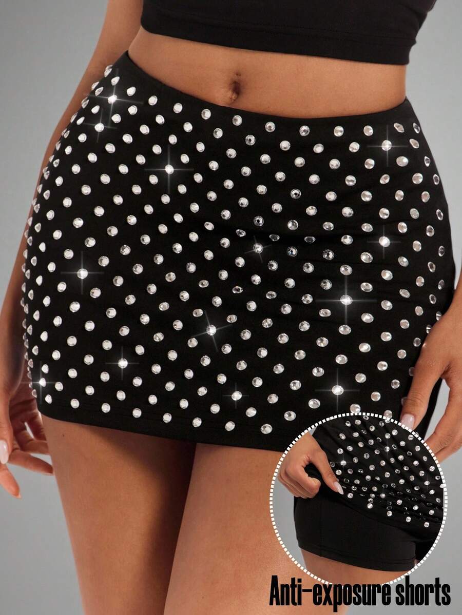 Women's black bodycon mini skort featuring a low waist, pleated side split hem, zipper closure, and built-in shorts.