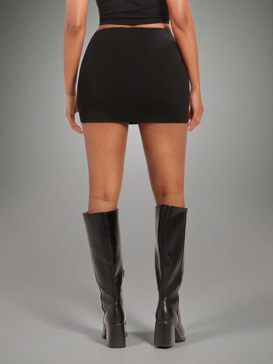 Women's black bodycon mini skort featuring a low waist, pleated side split hem, zipper closure, and built-in shorts.