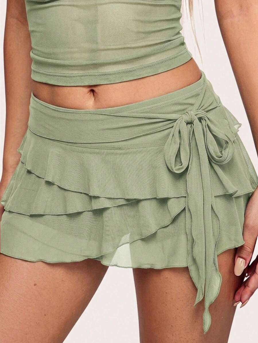 White tiered ruffle trim mini skirt for women with low waist, knot detail, mesh fabric, and casual Y2K boho design.