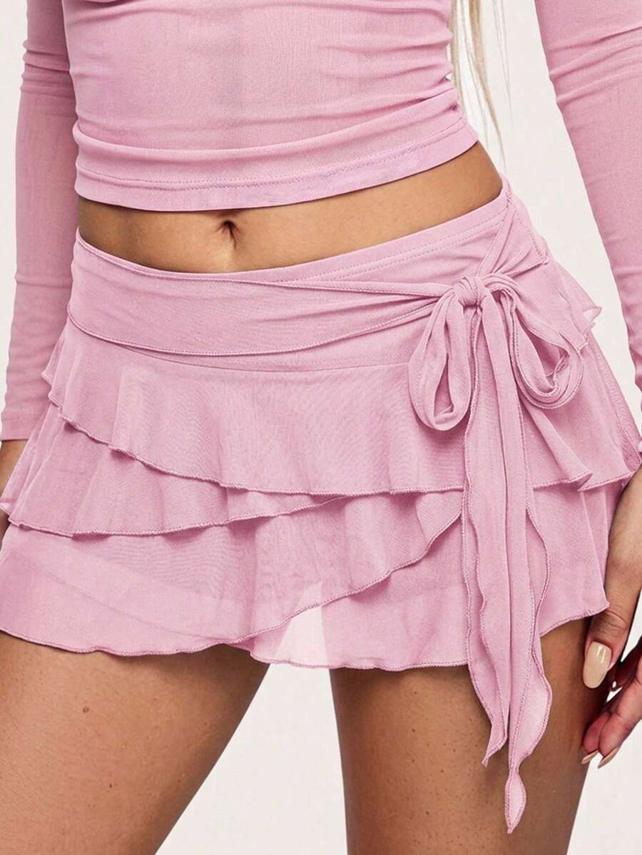White tiered ruffle trim mini skirt for women with low waist, knot detail, mesh fabric, and casual Y2K boho design.