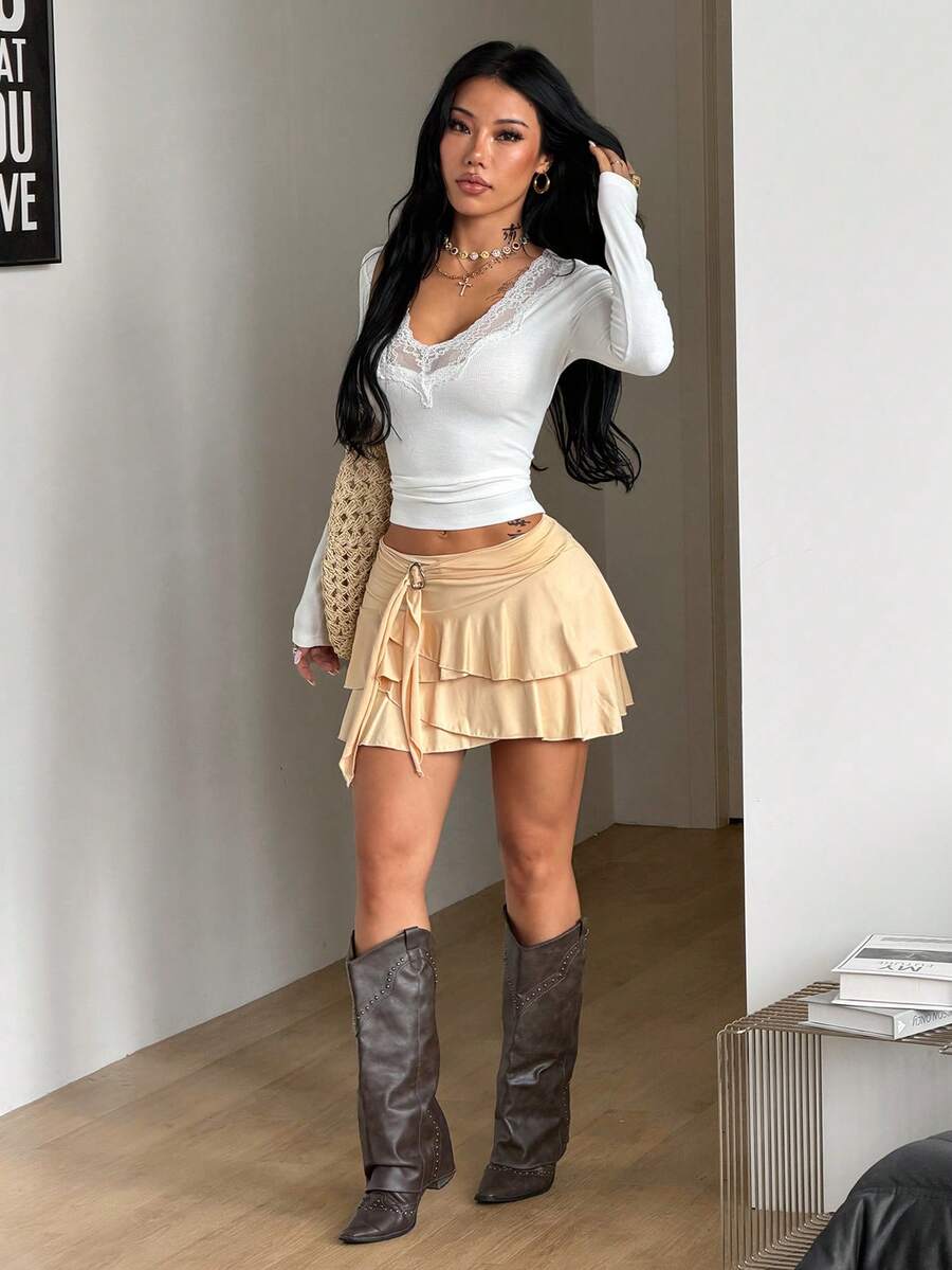 Black low waist tiered mini skirt featuring a ruffle hem and ring accent detail on knitted stretch fabric for women.