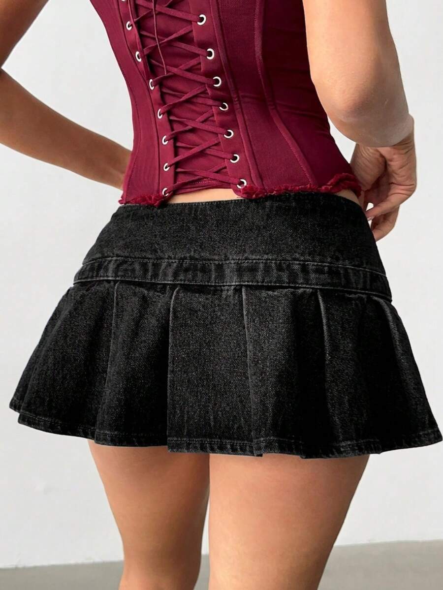 Women's blue denim pleated mini skirt skort featuring a low waist fit with zipper and grommet eyelet details.