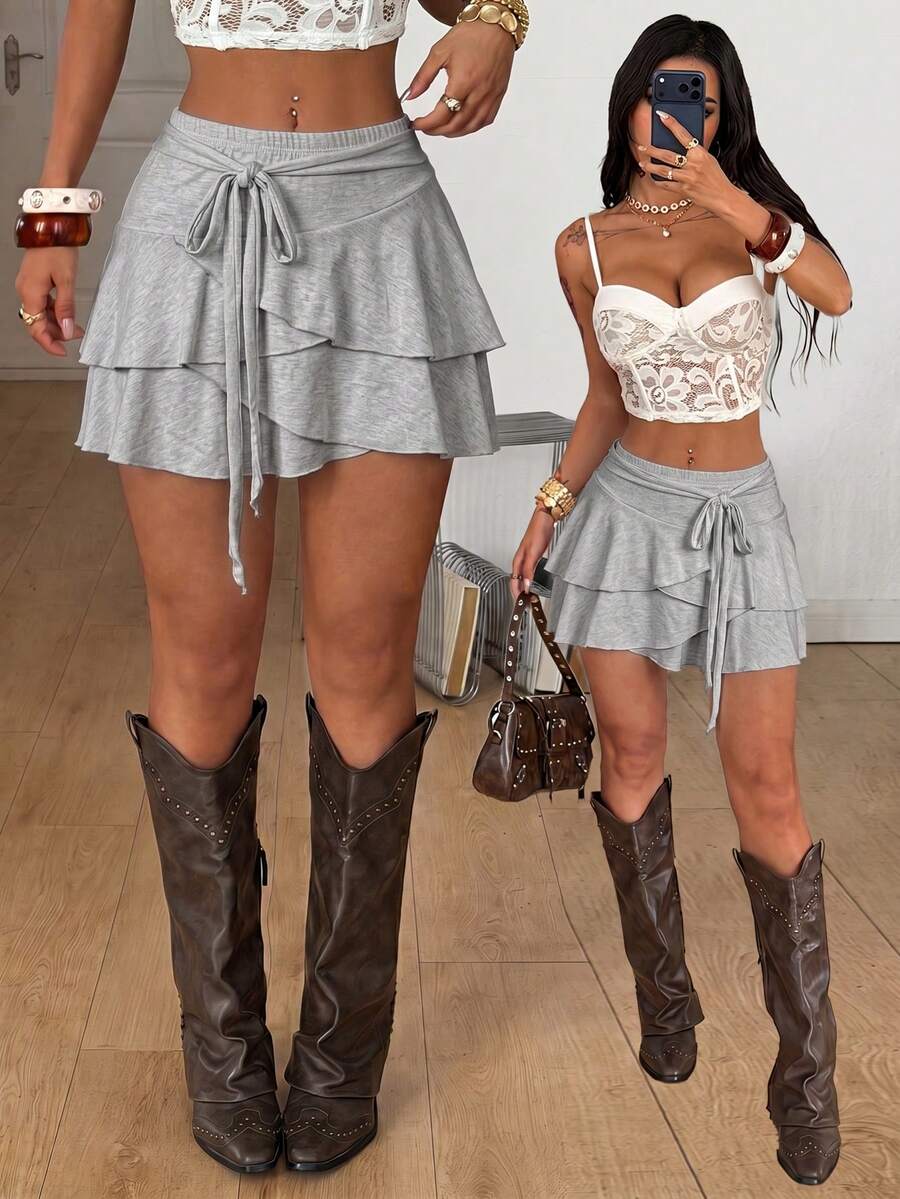 Black low waist tiered mini skirt featuring a ruffle hem and ring accent detail on knitted stretch fabric for women.