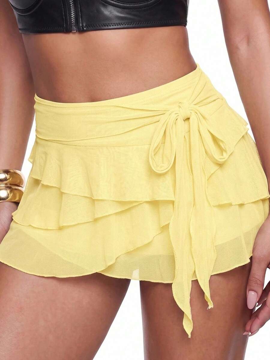 White tiered ruffle trim mini skirt for women with low waist, knot detail, mesh fabric, and casual Y2K boho design.