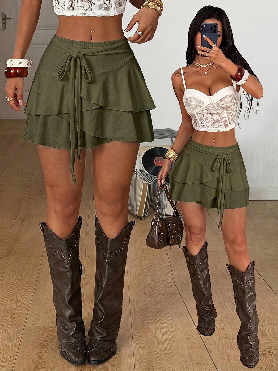 Black low waist tiered mini skirt featuring a ruffle hem and ring accent detail on knitted stretch fabric for women.